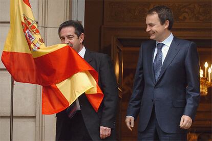 Miguel Ángel Revilla besa la bandera de España antes de reunirse con Zapatero en Moncloa.