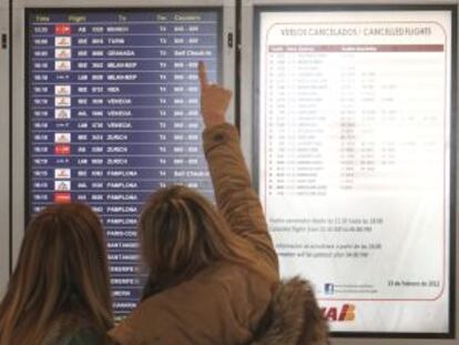 Dos mujeres miran los paneles de información en Barajas