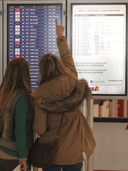 Dos mujeres miran los paneles de información en Barajas