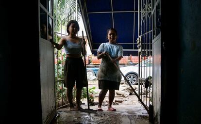 Dos mujeres limpian la entrada de su vivienda tras el paso de 'Agatha', en Santa María Tonameca, Oaxaca.