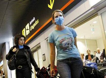 Pasajeras de un vuelo de México llegan ayer al aeropuerto de Madrid. Una lleva aún la mascarilla protectora.