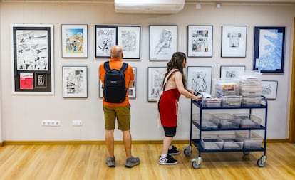 Un hombre observa ilustraciones enmarcadas en las paredes Akira Cómics, junto a una trabajadora de la tienda.