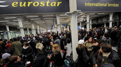 Pasajeros en la estación  de King Cross esperan a que se restablezca el servicio de ferrocarril en el Eurotúnel, ayer en Londres.
