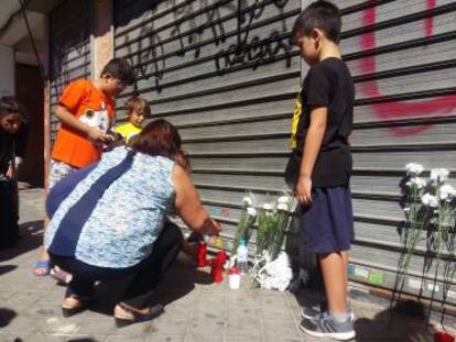 Varios vecinos encienden velas en la puerta del establecimiento donde murió el niño de tres años.