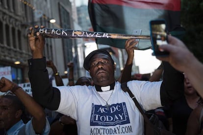 Un hombre sostiene un bate de béisbol donde se puede leer 'Poder Negro' durante la protesta en Dallas.