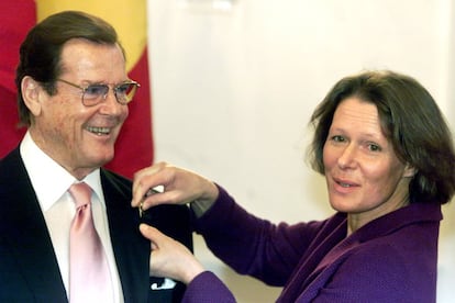Christina Rau, mujer del expresidente alemán Johannes Rau, le coloca la Medalla de Honor alemana en la chaqueta al actor británico y embajador de 'buena voluntad' de UNICEF, Roger Moore, en el palacio Bellevue, en Berlín (Alemania), el 10 de febrero de 2003.