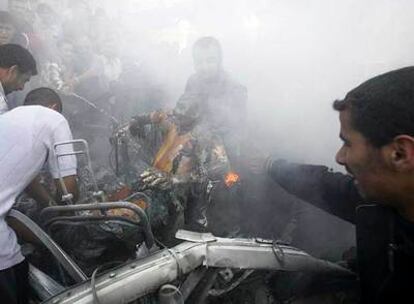 Varias personas sacan al ocupante de un coche destruido por un ataque aéreo israelí ayer en Gaza.