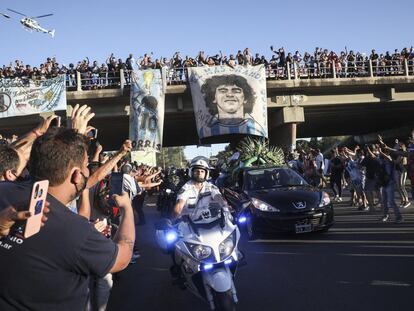 Cientos de aficionados saludan desde un paso elevado al coche fúnebre que lleva los restos de Diego Armando Maradona.