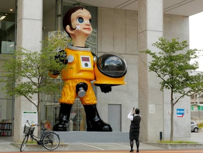 Una mujer toma una fotografía de la escultura gigante del niño con traje antirradiación, 'Sun Child', en Fukushima (Japón).