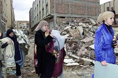 Varias mujeres portan bienes que han rescatado de entre las ruinas de sus viviendas en Imzuren.