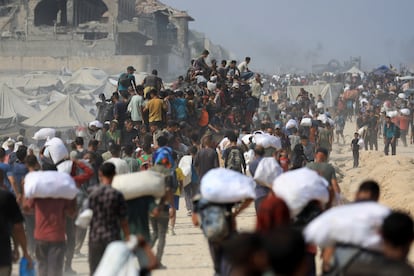 Cientos de ciudadanos palestinos transportan sacos con ayuda humanitaria recogida de los camiones que han llegado a la Franja a través de Israel, este domingo.