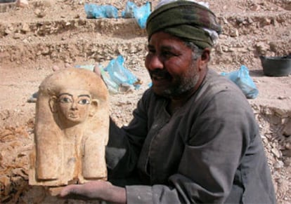 Un trabajador egipcio muestra el trozo de sarcófago hallado por la misión española.