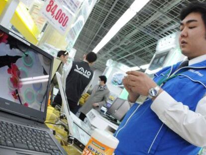 Un empleado limpia un ordenador NEC en una tienda de Tokio.