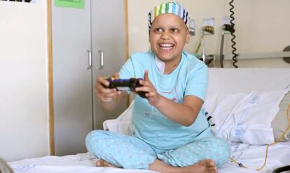 Una niña con cáncer juega a un videojuego en su habitación del hospital.