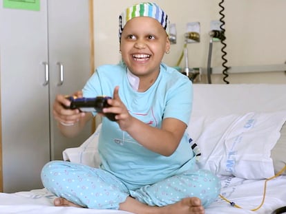 Una niña con cáncer juega a un videojuego en su habitación del hospital.