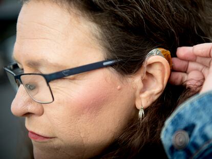 A woman shows her hearing aid.