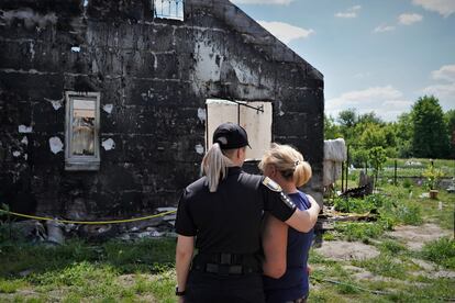La agente Olga Yuskevich trata de consolar a Liubov, una cocinera de 60 años, delante de los restos de su casa