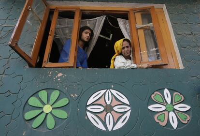 Kashmiris watch a protest against alleged killing of civilians by government forces, through the window of their home, in Srinagar, Indian controlled Kashmir, Friday, Aug. 19, 2016. Curfew and protests have continued across the valley amidst outrage over the killing of a top rebel leader by Indian troops in early July, 2016. (AP Photo/Mukhtar Khan)