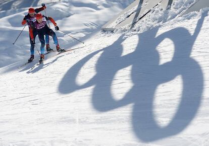 Los rusos Alexander Legkov and Ilia Chernousov participantes en las pruebas de esquí de fondo pasan por la sombra que los anillos olímpicos proyectan en la nieve. 