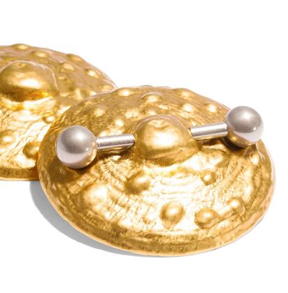 Siguiendo esta tendencia, Schiaparelli cuenta con diferentes modelos de joyas con forma de pezón. Estos pendientes son de latón dorado con un piercing en plata.