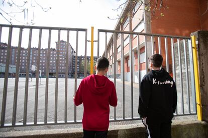 Dos adolescentes observan el patio cerrado de un colegio de Vitoria durante el confinamiento
