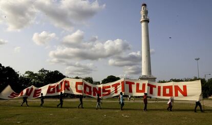 Membros dos sindicatos de esquerda andam com uma faixa que diz "salve nossa constituição" em frente ao monumento da cidade, Shaheed Minar, antes conhecido como Monumento Ochterlony, durante uma manifestação em 1º de maio em Calcutá (Índia).