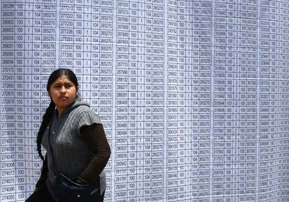 Una mujer camina frente a la lista de votación en Lima