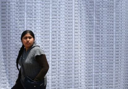 Una mujer camina frente a la lista de votaci&oacute;n en Lima 