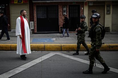 Un sacerdote católico junto a soldados del Ejército de Colombia, en una calle de Bogotá, en abril de 2023.