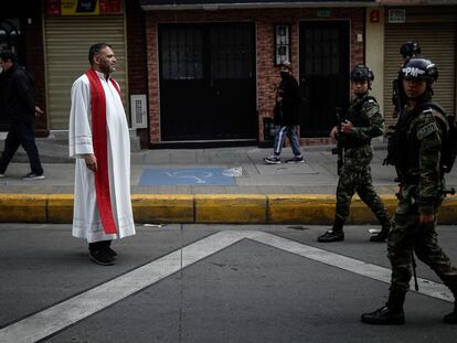 Un sacerdote católico junto a soldados del Ejército de Colombia, en una calle de Bogotá, en abril de 2023.