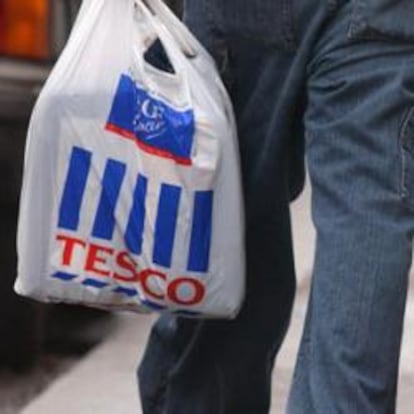 Una persona camina por la calle con dos bolsas de plástico.