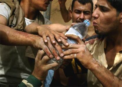 Un grupo de civiles iraquíes pugnan por una botella de agua potable en el centro de Bagdad.