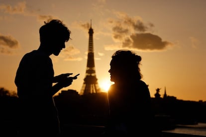 Una pareja disfruta de la vista de la Torre Eiffel al atardecer en París.