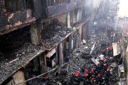 Bombeiros se reúnem ao redor dos edifícios incendiados na noite nesta quarta-feira.