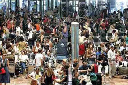 Cientos de pasajeros esperan sus vuelos ayer en el aeropuerto de El Prat de Barcelona.