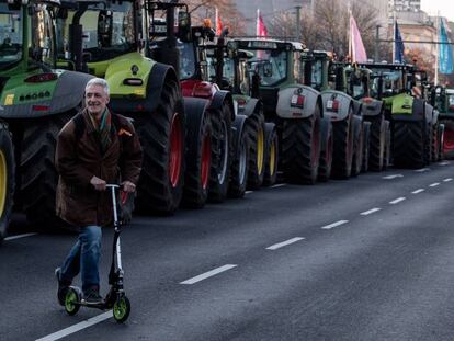 Un hombre pasa en patinete eléctrico delante a decenas de tractores parados en Berlín, en enero.