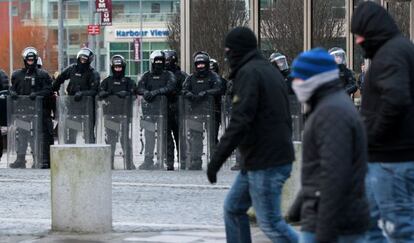 Policía antidisturbios vigila en Belfast a un grupo de encapuchados.