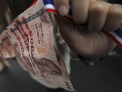 Un opositor al gobierno tailandés muestra unos billetes durante una manifestación en el centro de Bangkok, Tailandia, la capital del país se encuentra en estado de emergencia desde el miércoles.