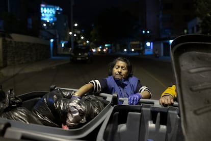 Una mujer saca bolsas de basura de los contenedores para abrirlas, en Quito, en agosto de 2019.