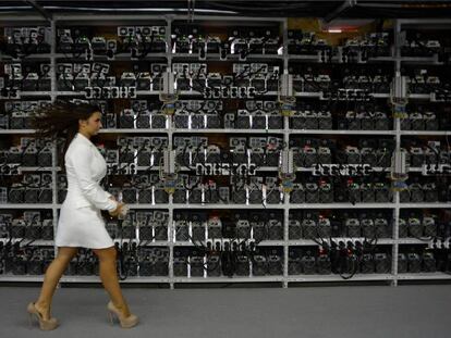Una mujer camina delante de máquinas para la producción de bitcoins y lightcoins en una feria celebrada en Rusia. Le convendría una talla menos de zapatos.