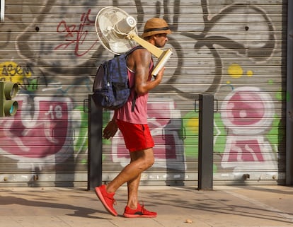 Un hombre con un ventilador por una calle de Sevilla, en julio. 