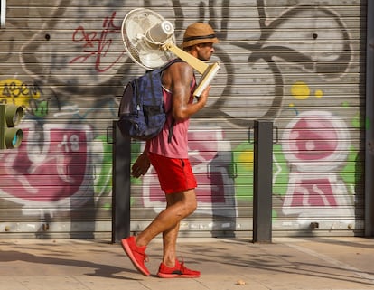 Un hombre con un ventilador por una calle de Sevilla, en julio.
