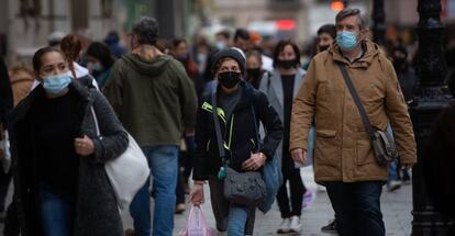 Viandantes caminan con bolsas por una vía de Barcelona.