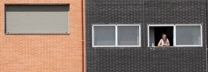 Una vecina se asoma a una ventana del edificio Memoria, de la EMVS, en la calle de Barrileros.