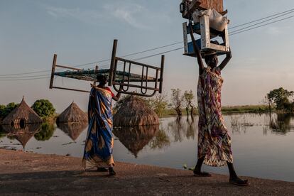 Las mujeres cargan muebles y bienes en una zona inundada del Estado de Unity.