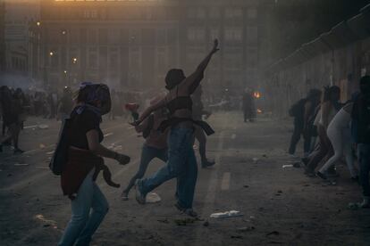 Mujeres lanzan objetos contra las barricadas que colocó el gobierno de la Ciudad de México en el Zócalo.