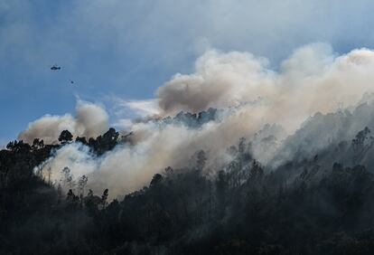 Un helicóptero lanza agua sobre la zona del incendio en el municipio de Baiao, este lunes. 