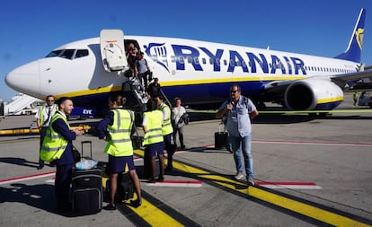 Tripulantes de cabina de pasajeros de Ryanair, a pie de pista, ante un avión de la compañía.