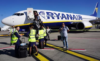 Tripulantes de cabina de pasajeros de Ryanair, a pie de pista, ante un avi&oacute;n de la compa&ntilde;&iacute;a.