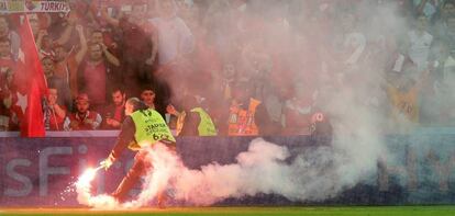 Un empleado de la UEFA retira una bengala.